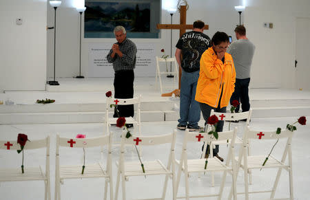 People react as they look at chairs showing where the Holcolmbe family and others were found dead at the First Baptist Church of Sutherland Springs where 26 people were killed one week ago, as the church opens to the public as a memorial to those killed, in Sutherland Springs, Texas, U.S. November 12, 2017. REUTERS/Rick Wilking