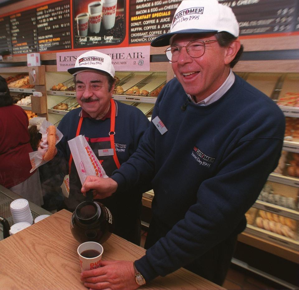 QUINCY, MA - JANUARY 31: Dunkin' Donuts CEO Bob Rosenberg pours a customer coffee as actor Michael Vale who plays "Fred the Baker" in TV commercials gets ready with a donut at the original Dunkin' Donuts location in Quincy, MA on Jan. 31, 1995. Rosenberg used to work at this store in 1959. (Photo by David L. Ryan/The Boston Globe via Getty Images)