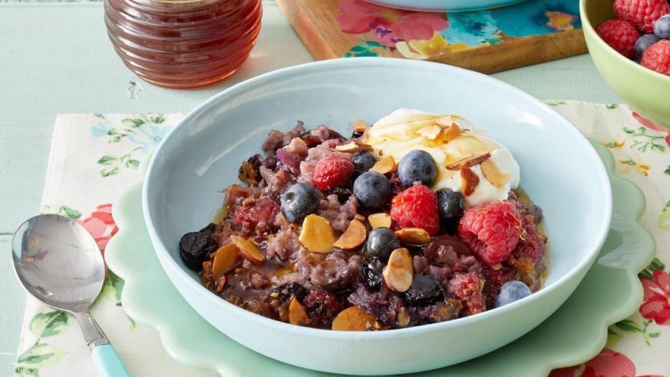 a bowl of cereal with milk and berries on a table