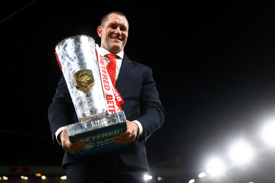 MANCHESTER, ENGLAND - SEPTEMBER 24: Kristian Woolf, Head Coach of St Helens, poses for a photograph with the Betfred Super League Grand Final Trophy as players of St Helens celebrates their side's win after the final whistle of the Betfred Super League Grand Final match between St Helens and Leeds Rhinos at Old Trafford on September 24, 2022 in Manchester, England. (Photo by Michael Steele/Getty Images)