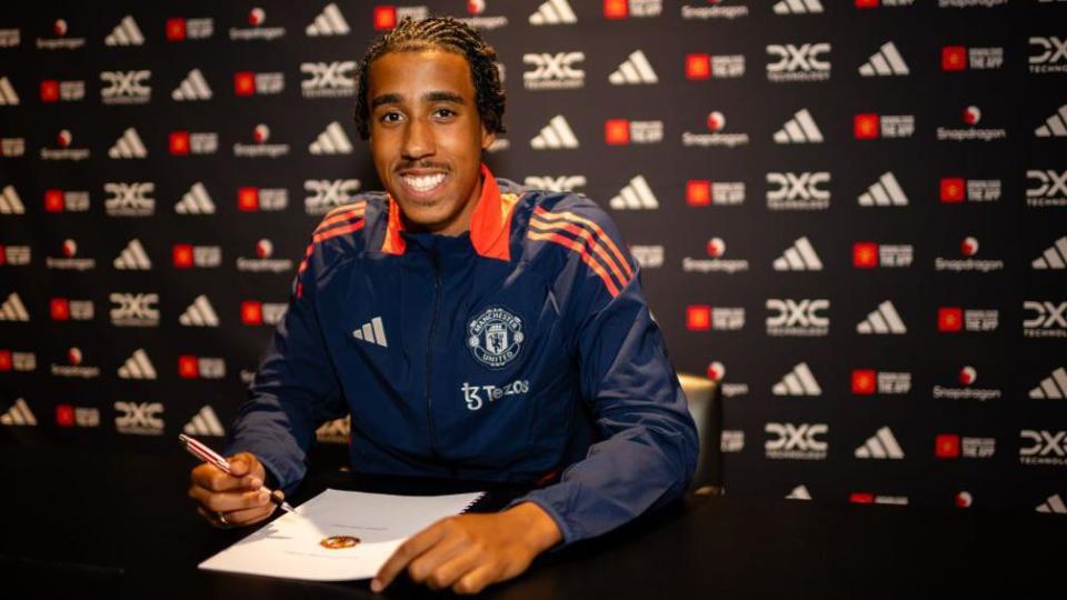 Leny Yoro poses with his contract with Manchester United