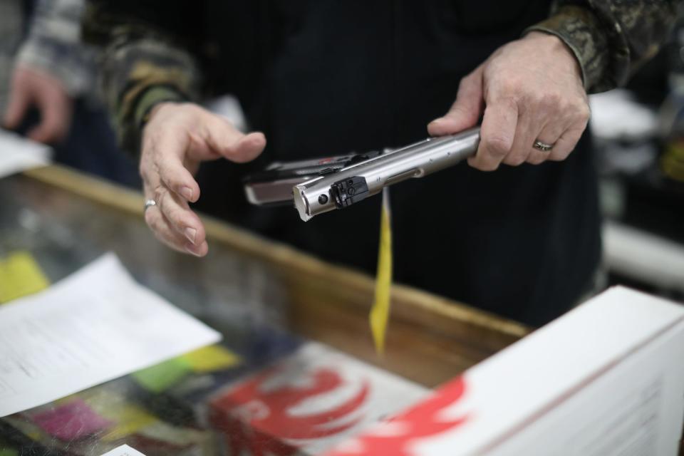 A salesman takes a Ruger out of the case to look at, during the Novi Gun and Knife Show at Suburban Collection Showplace in Novi, Mich. on Feb. 24, 2018.
