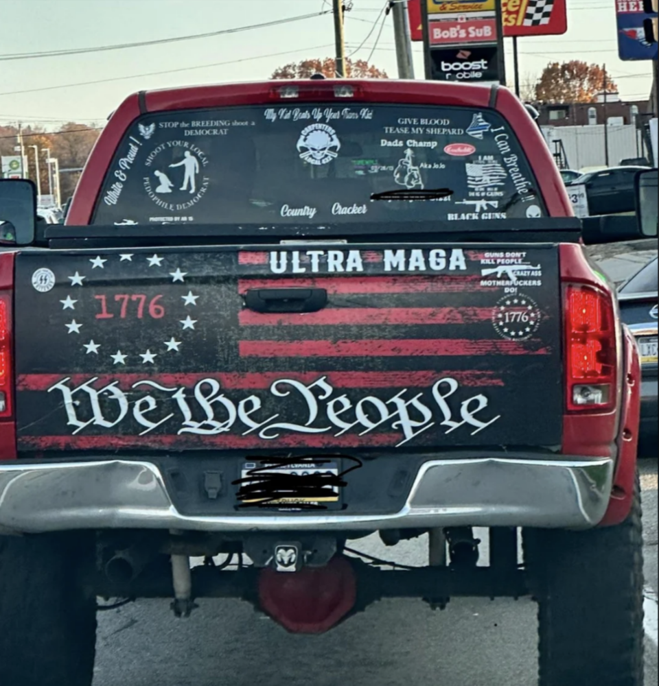 Rear view of a truck with "ULTRA MAGA" and "We the People" decals, alongside various patriotic and political stickers