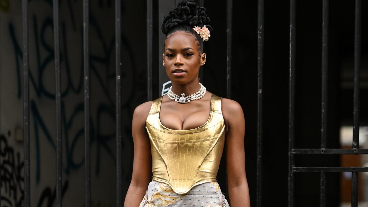 Didi Stone is seen wearing a gold Vivienne Westwood top and skirt and gold strapped heels outside the Vivienne Westwood show during Paris Fashion Week S/S 2022 on October 02, 2021 in Paris, France