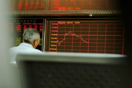 A man sits in front of a board showing market information at a securities brokerage house in Beijing