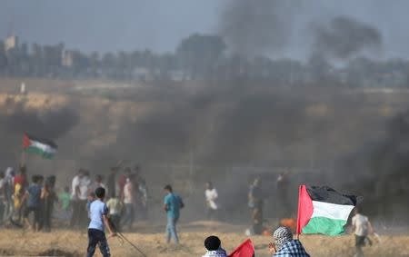 Demonstrators wave Palestinian flag during a protest at the Israel-Gaza border in the southern Gaza Strip July 6, 2018. REUTERS/Ibraheem Abu Mustafa