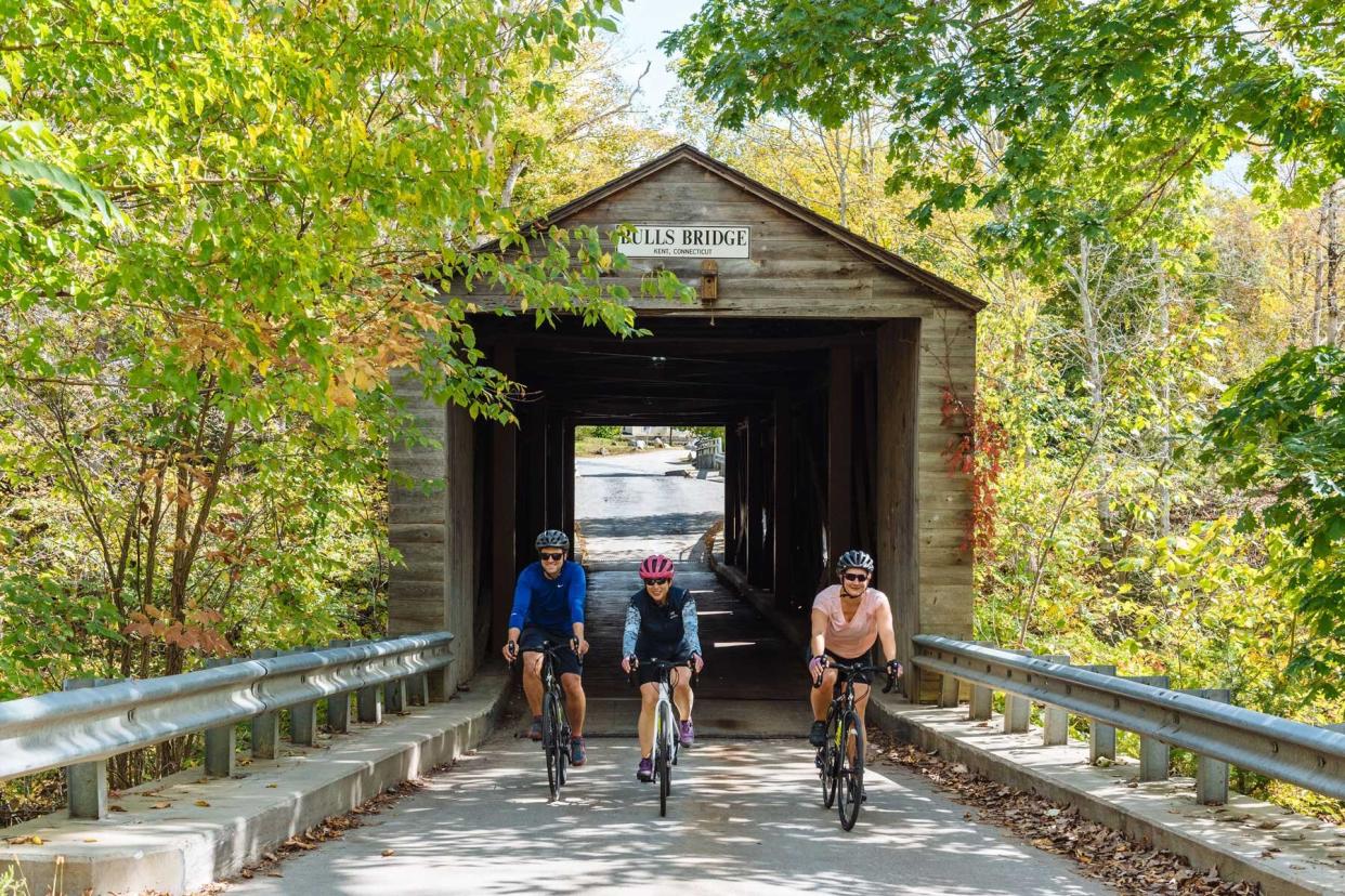 Cyclists ride over a covered bridge in Kent, Connecticut
