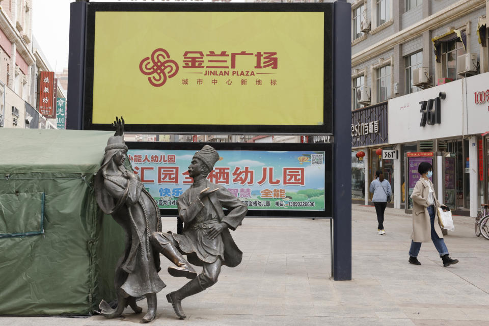 Pedestrians walk by statutes depicting Uyghurs in traditional garb dancing on a shopping street in Aksu, in northwestern China's Xinjiang Uyghur Autonomous Region, on March 18, 2021. Four years after Beijing's brutal crackdown on largely Muslim minorities native to Xinjiang, Chinese authorities are dialing back the region's high-tech police state and stepping up tourism. But even as a sense of normality returns, fear remains, hidden but pervasive. (AP Photo/Ng Han Guan)