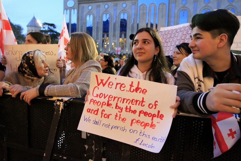 Protesters with a poster gather outside the parliament building in Tbilisi, Georgia, on Tuesday, April 16, 2024, to protest against "the Russian law" similar to a law that Russia uses to stigmatize independent news media and organizations seen as being at odds with the Kremlin. (AP Photo/Shakh Aivazov)