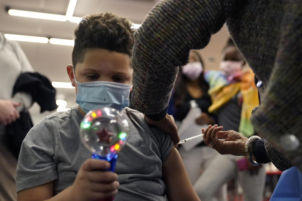 Jonathan Rodriguez, 6, of Worcester, Mass., focuses on a spinning toy as he receives a shot of the Pfizer COVID-19 vaccine, Thursday, Dec. 2, 2021, at a Worcester Department of Health & Human Services mobile vaccination clinic, in Worcester. As the U.S. recorded its first confirmed case of the omicron variant, doctors across the country are experiencing a more imminent crisis with a delta variant that is sending record numbers of people to the hospital in New England and the Midwest. (AP Photo/Steven Senne)