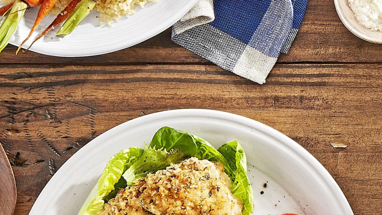 roasted parmesan chicken on a bed of lettuce with roasted tomatoes on the side