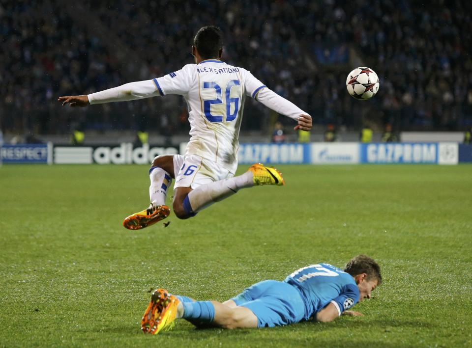 Zenit St Petersburg's Oleg Shatov (bottom) lies on the pitch as Porto's Alex Sandro jumps above during their Champions League soccer match at the Petrovsky stadium in St. Petersburg November 6, 2013. REUTERS/Alexander Demianchuk (RUSSIA - Tags: SPORT SOCCER)