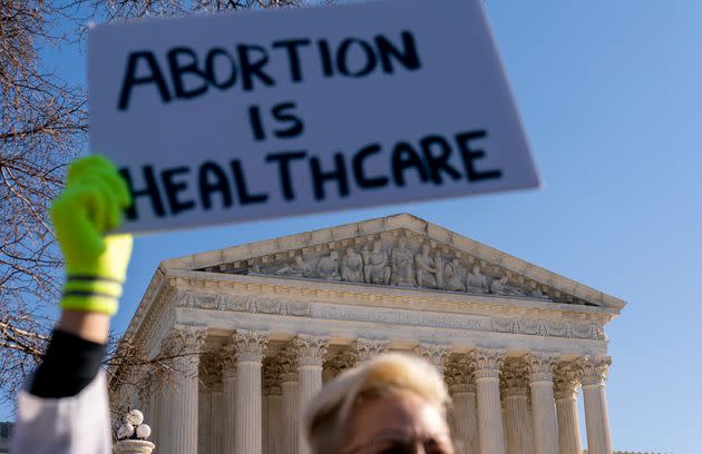 A woman in a doctors uniform holds a poster that reads 