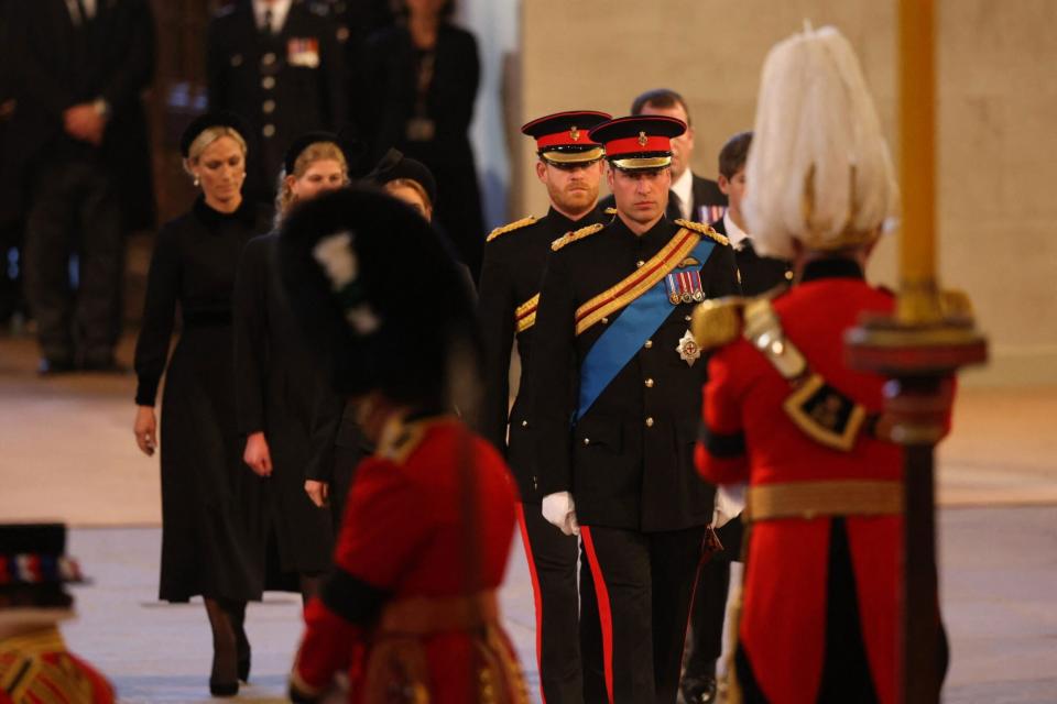 Britain's Prince William (C-R), Prince of Wales, and Britain's Prince Harry (C-L), Duke of Sussex, arrive to mount a vigil around the coffin of Queen Elizabeth II, draped in the Royal Standard with the Imperial State Crown and the Sovereign's orb and sceptre, lying in state on the catafalque in Westminster Hall, at the Palace of Westminster in London on September 16, 2022, ahead of her funeral on Monday. - Queen Elizabeth II will lie in state in Westminster Hall inside the Palace of Westminster, until 0530 GMT on September 19, a few hours before her funeral, with huge queues expected to file past her coffin to pay their respects. (Photo by Ian Vogler / POOL / AFP) (Photo by IAN VOGLER/POOL/AFP via Getty Images)