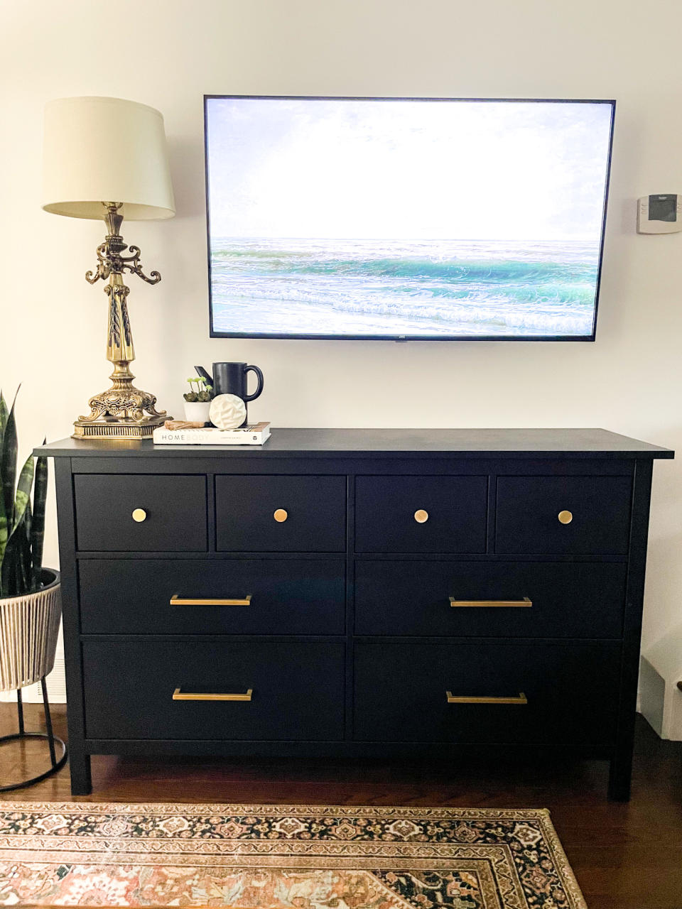 black chest of drawers with gold handles and a persian rug