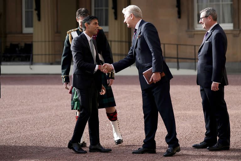 New Conservative Party leader and incoming prime minister Rishi Sunak (2L) is greeted as he arrives at Buckingham Palace in London on October 25, 2022, for an audience with King Charles III, where he will be invited to orm a government. - Rishi Sunak will on Tuesday be appointed Britain's third prime minister this year, after outgoing leader Liz Truss submitted her resignation to King Charles III. (Photo by Yui Mok / POOL / AFP)