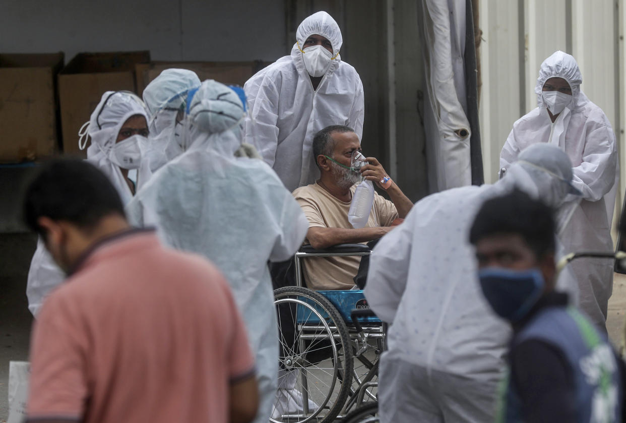 Health workers attend to a patient at the Jumbo COVID-19 filed hospital in Mumbai, India, Monday, April 26, 2021. New infections are rising faster in India than any other place in the world, stunning authorities and capsizing its fragile health system. (AP Photo/Rafiq Maqbool)