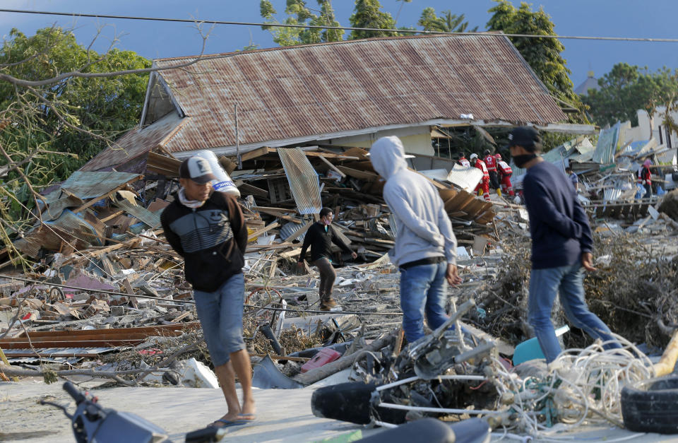 People survey the damage to a residential area following a massive earthquake and tsunami at Talise beach in Palu, Central Sulawesi, Indonesia, Monday, Oct. 1, 2018. A mass burial of earthquake and tsunami victims was being prepared in a hard-hit city Monday as the need for heavy equipment to dig for survivors of the disaster that struck a central Indonesian island three days ago grows desperate. (AP Photo/Tatan Syuflana)