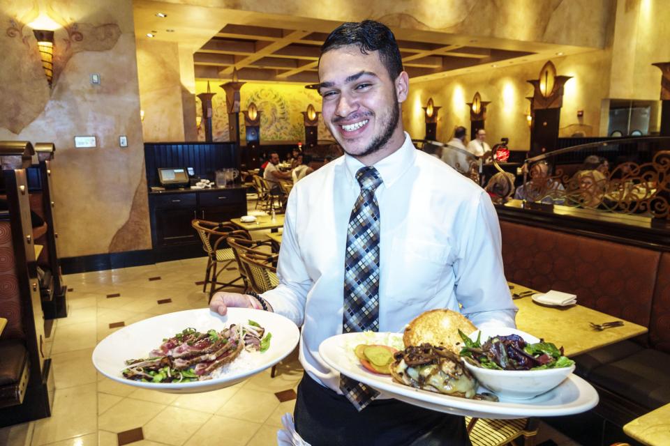 West Palm Beach, CityPlace, Cheesecake Factory food runner with plates. (Photo by: Jeffrey Greenberg/Universal Images Group via Getty Images)