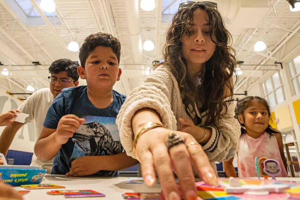 Volunteer Anyela Ventura, 18, plays a game with Moises Isaac, 8, while Isaac's parents take an English reading class at Milton Elementary School in Milton, Delaware, on Thursday, Oct. 26, 2023.