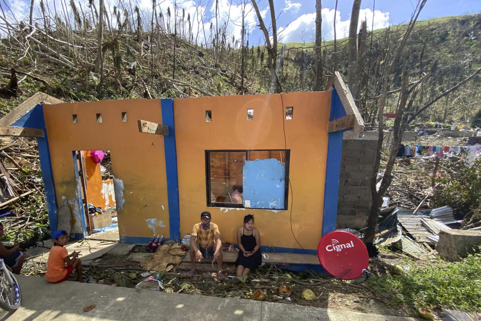 In this photo provided by Greenpeace, residents sit beside damaged homes due to Typhoon Rai in Surigao City, southern Philippines Monday Dec. 20, 2021. The governor of a central Philippine province devastated by Typhoon Rai last week pleaded on radio Tuesday for the government to quickly send food and other aid, warning that without outside help, army troops and police forces would have to be deployed to prevent looting amid growing hunger. (Erwin Mascarinas/Greenpeace via AP)