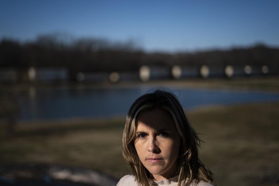 Jessica Conard poses for a photograph as a train roles by her home in East Palestine, Ohio, Tuesday, March 7, 2023. She wonders after the train derailment if her kids will ever be able to fish in the pond separating their property from the railroad tracks. Or play at the park where the chemicals are being removed from a stream. Can they remain in the town where "generations upon generations" of family have lived? (AP Photo/Matt Rourke)