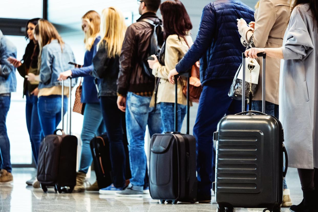 Line of people waiting at the airport with their luggage