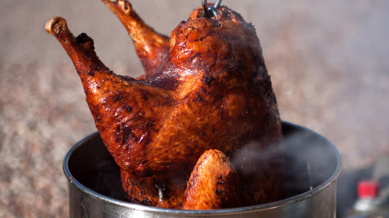 Removing a cooked turkey from frying pot