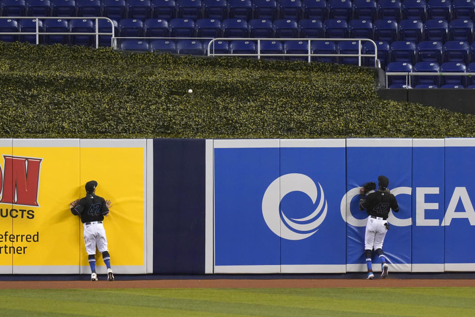 Outfielders Jon Berti, left, and Lewis Brinson watch as a ball hit by Tampa Bay Rays' Yoshitomo Tsutsugo goes over the wall for a two-run home run during the first inning of a baseball game, Sunday, Aug. 30, 2020, in Miami. (AP Photo/Wilfredo Lee)