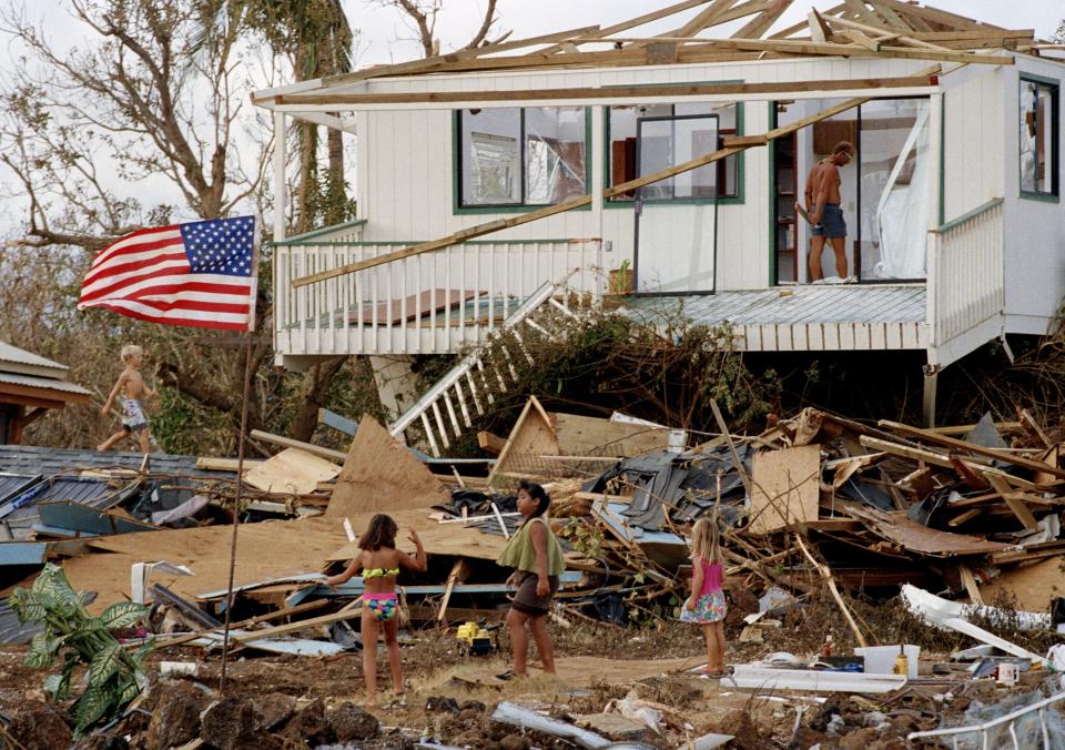 FILE - Children play in the rubble left by the fury of Hurricane Iniki, Sept. 15, 1992, at Brennecke's Beach near Poipu Beach, Hawaii, on the island of Kauai. Forecasters say this year's hurricane season for waters around Hawaii will likely be “below-normal” with one to four tropical cyclones across the central Pacific region. (AP Photo/Reed Saxon, File)