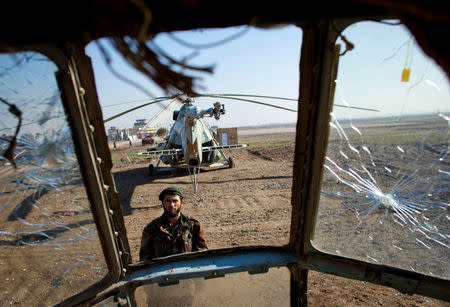 A soldier of the Afghan National Army (ANA) is seen through the cockpit of a derelict Russian helicopter as he guards Kunduz airport December 10, 2011. REUTERS/Thomas Peter