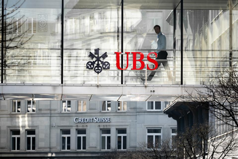 A employee is seen in silhouette next to a sign of Swiss giant banking UBS and a sign of Credit Suisse bank in Zurich on March 20, 2023. - UBS share price plunged on March 20, 2023 as a deal to take over its troubled Swiss rival Credit Suisse for $3.25 billion failed to calm stock market nerves. (Photo by Fabrice COFFRINI / AFP) (Photo by FABRICE COFFRINI/AFP via Getty Images)