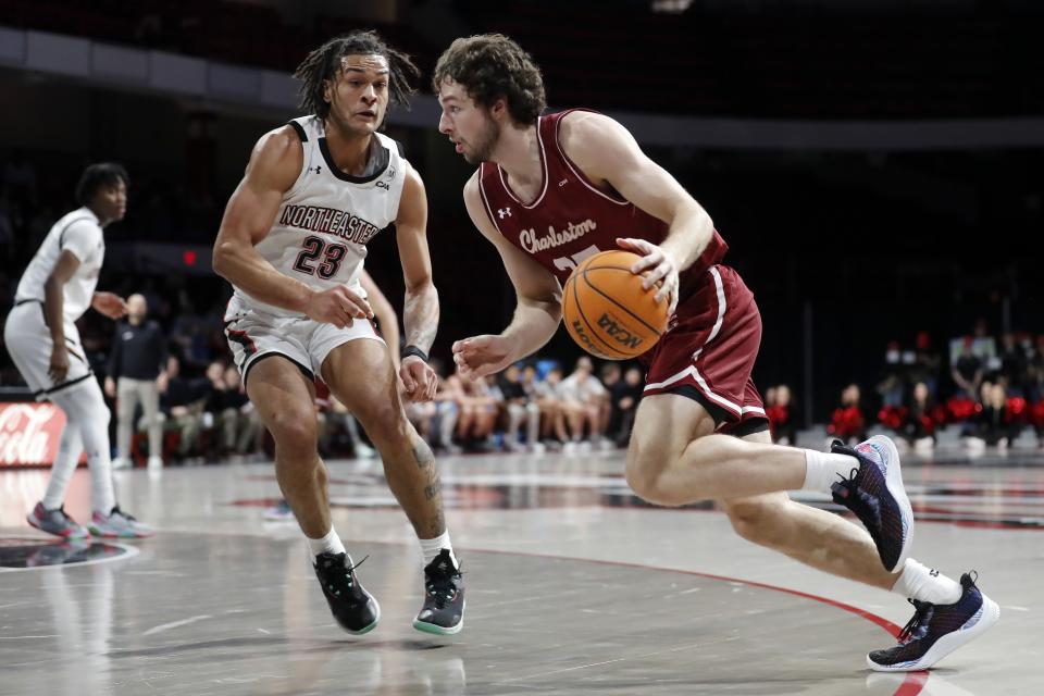 Charleston's Ben Burnham (25) drives past Northeastern's Joe Pridgen (23) during the first half of an NCAA college basketball game, Saturday, Jan. 21, 2023, in Boston. (AP Photo/Michael Dwyer)