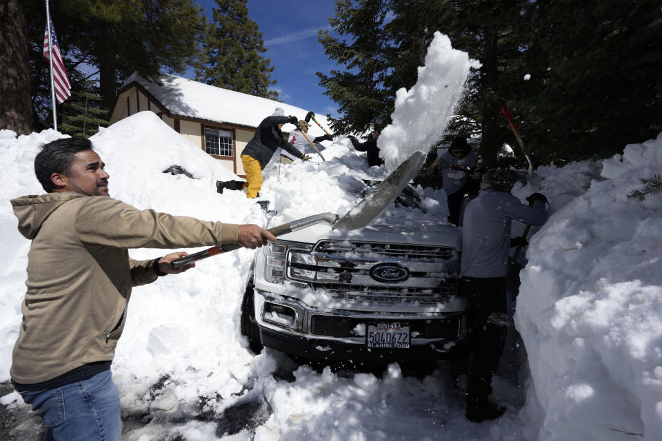 Rob Pagarian, at left, and fellow volunteers with the disaster response group Team Rubicon dig a resident's vehicle out of the snow Wednesday, March 8, 2023, in Lake Arrowhead, Calif. (AP Photo/Marcio Jose Sanchez)