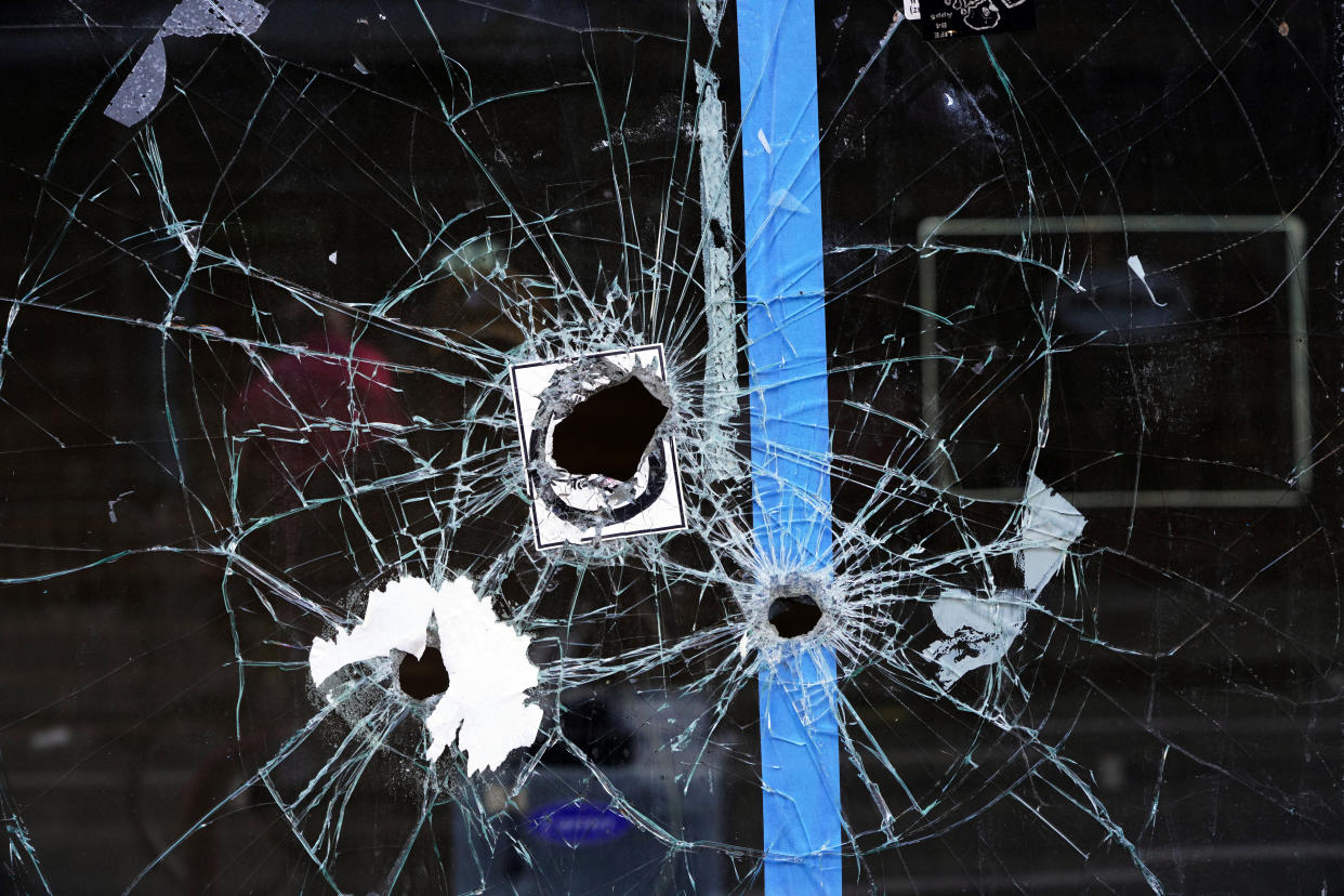 A storefront window with bullet holes.