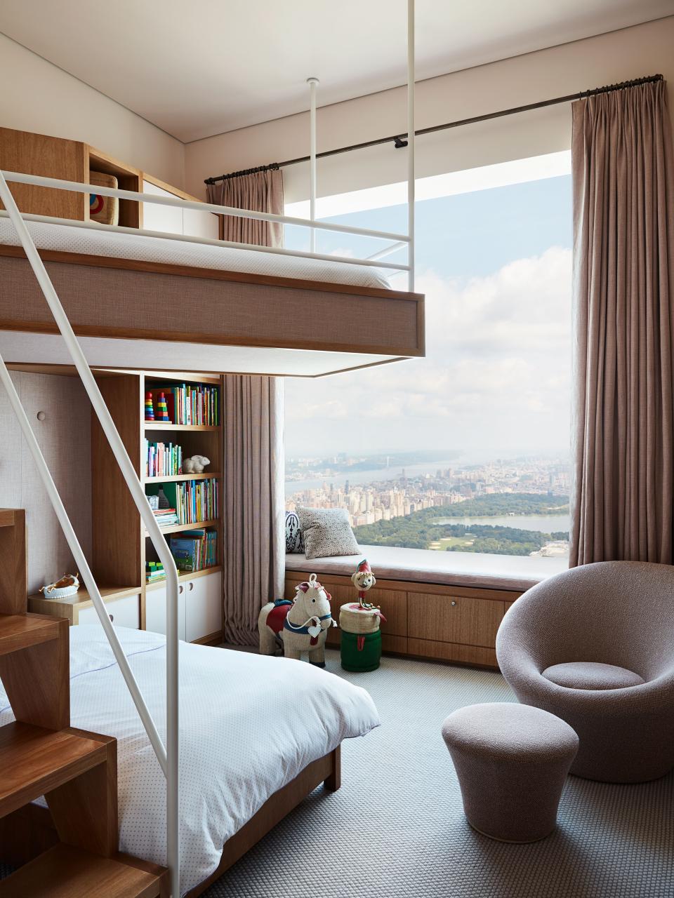 A child’s bedroom has a custom bleached-mahogany bunk bed with D. Porthault linens, a Pierre Paulin chair covered in Maharam fabric, wool carpet by Stark, and curtains in a Kerry Joyce linen.