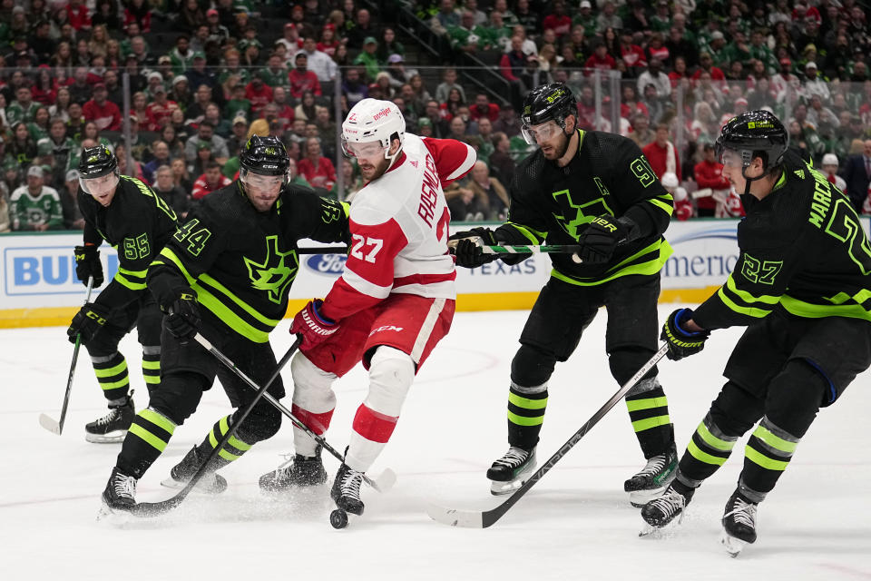 Detroit Red Wings center Michael Rasmussen (27) attempts to take control of the puck in front of Dallas Stars' Joel Hanley (44), Thomas Harley (55), Tyler Seguin (91) and Mason Marchment (27) in the second period of an NHL hockey game in Dallas, Monday, Dec. 11, 2023. (AP Photo/Tony Gutierrez)
