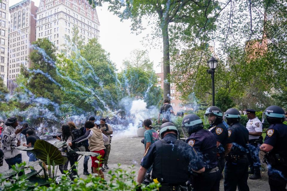 Police officers set off a smoke bomb in order to disperse a crowd, Friday, Aug. 4, 2023, in New York's Union Square. Police in New York City struggled to control a crowd of thousands of people who gathered in Manhattan's Union Square for an Internet personality's videogame console giveaway that got out of hand.