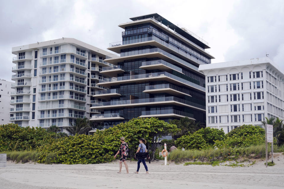Beachgoers walk by the beach entrance to the Arte by Antonio Citterio condominium, center, Tuesday, June 29, 2021, in Surfside, Fla. Jared Kushner and Ivanka Trump rent an apartment at Arte while their home is under construction at nearby Indian Creek Village. (AP Photo/Marta Lavandier)