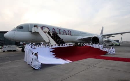 FILE PHOTO: Qatar Airways staff hold a Qatari flag in front of an Airbus A350-1000 at Hamad International Airport in Doha, Qatar, February 21, 2018. REUTERS/Naseem Zeitoon/File Photo