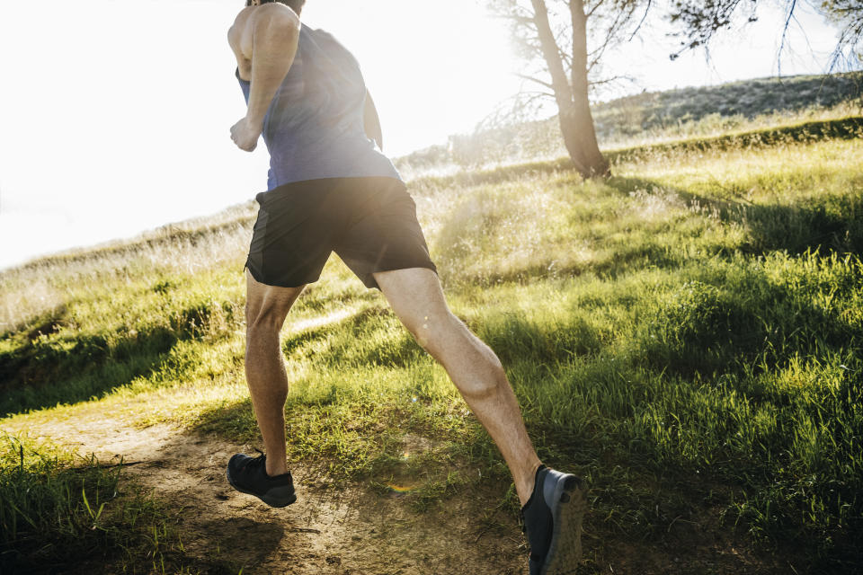 Person jogging on a grassy path with sunlight ahead