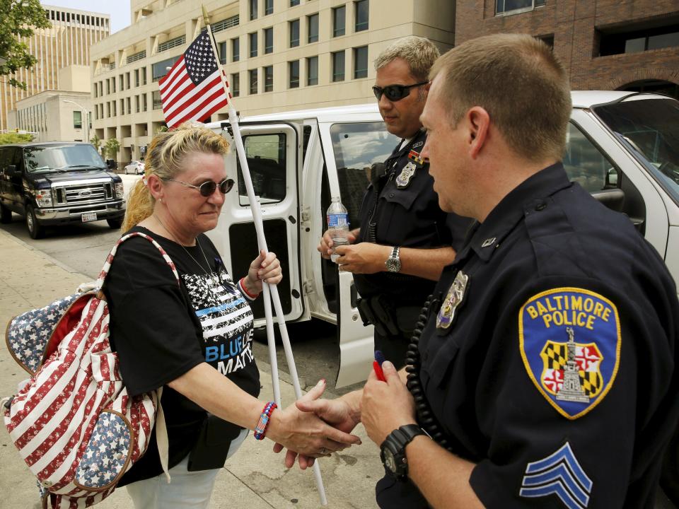 Police supporter Charlotte Britt (L) thanks Baltimore police officers and gives them felt hearts as gifts after a