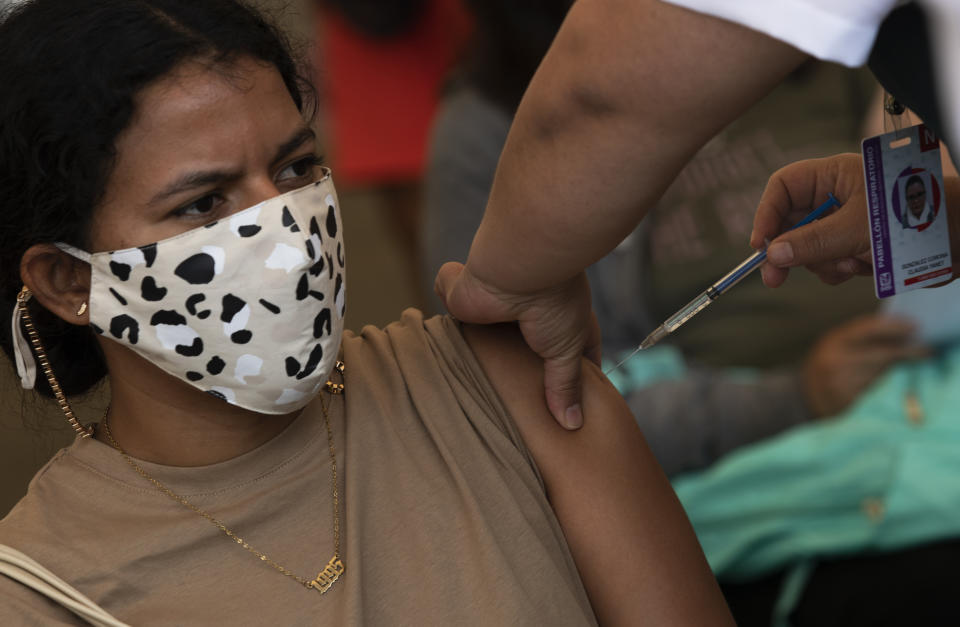 A healthcare worker injects a teacher with a dose of the CanSino COVID-19 vaccine, on the grounds of the National Polytechnic Institute, in Mexico City, Tuesday, May 18, 2021. Mexico is mounting a final push to get all of the country's school teachers vaccinated so that it can reopen schools, perhaps by June. (AP Photo/Marco Ugarte)