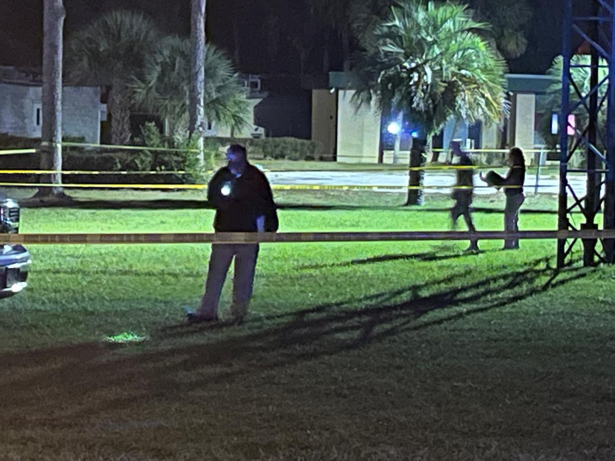 FDLE agent searching the area of Tuesday's shooting with a flashlight