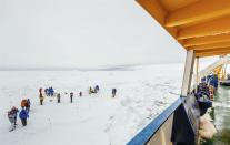 In this image provided by Australasian Antarctic Expedition/Footloose Fotography, people gather on the ice next the Russian ship MV Akademik Shokalskiy that is trapped in thick Antarctic ice 1,500 nautical miles south of Hobart, Australia, Friday, Dec. 27, 2013. The research ship, with 74 scientists, tourists and crew on board, has been on a research expedition to Antarctica, when it got stuck Tuesday after a blizzard's whipping winds pushed the sea ice around the ship, freezing it in place. (AP Photo/Australasian Antarctic Expedition/Footloose Fotography, Andrew Peacock) EDITORIAL USE ONLY