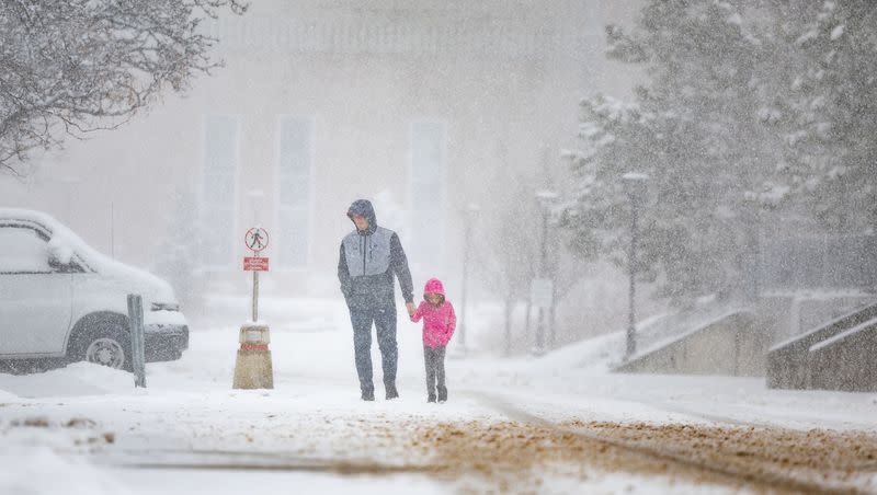 Brock Peery and his daughter Berkley, 6, walk back to their car during a snowstorm in Salt Lake City on Friday, March 24, 2023. Utah has achieved a record-breaking snowfall total this winter, according to the National Weather Service.