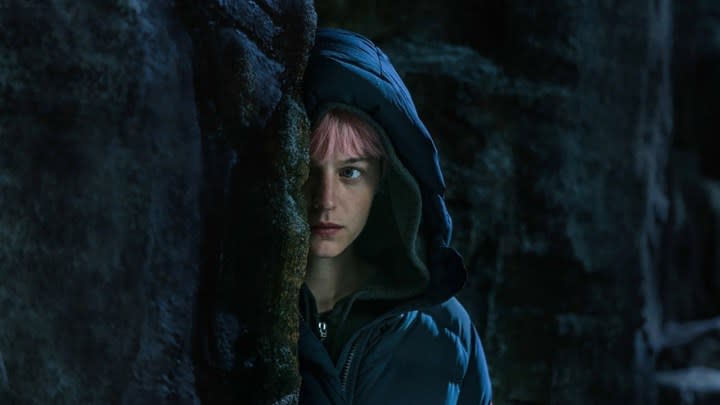 Emma Corrin as Darby in A Murder at the End of the World hiring in a corner with pink hair and a black hoodie.