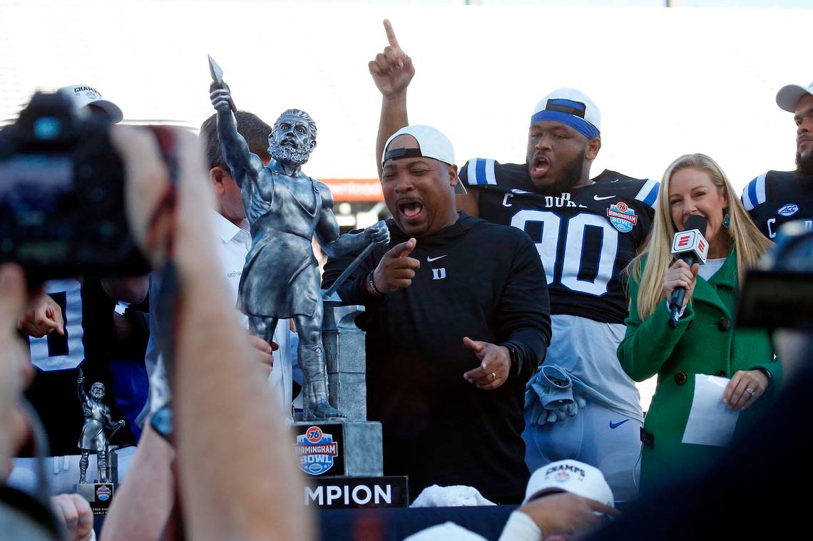 Dec 23, 2023; Birmingham, AL, USA; Duke Blue Devils interim head coach Trooper Taylor and all-ACC defensive tackle DeWayne Carter react as they are presented with the Birmingham Bowl trophy after defeating the Troy Trojans at Protective Stadium.