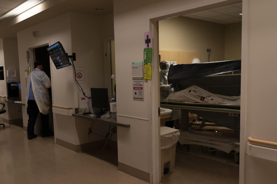 FILE - Transporter Jo Navarro, right, prepares to move a body of a COVID-19 victim to a morgue at Providence Holy Cross Medical Center in Los Angeles, Dec. 14, 2021. The U.S. death toll from COVID-19 has hit 1 million, less than 2 1/2 years into the outbreak. (AP Photo/Jae C. Hong, File)