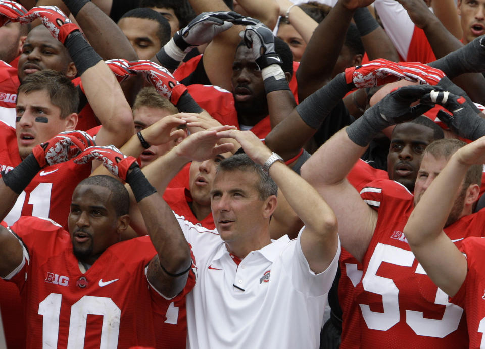 FILE - In this Sept. 1, 2012, file photo, Ohio State NCAA college football head coach Urban Meyer leads the team in singing Carmen Ohio after beating Miami of Ohio 56-10, in Columbus, Ohio. Ohio State suspended coach Urban Meyer for three games on Wednesday night, Aug. 22, 2018, for mishandling repeated professional and behavioral problems of an assistant coach, with investigators finding Meyer protected his protege for years through domestic violence allegations, a drug problem and poor job performance. The superstar coach's treatment of his now-fired assistant was also clouded by his abiding devotion to the legacy of former Ohio State coach Earle Bruce, the grandfather of former wide receivers coach Zach Smith and an early coaching mentor for Meyer. (AP Photo/Jay LaPrete, File)